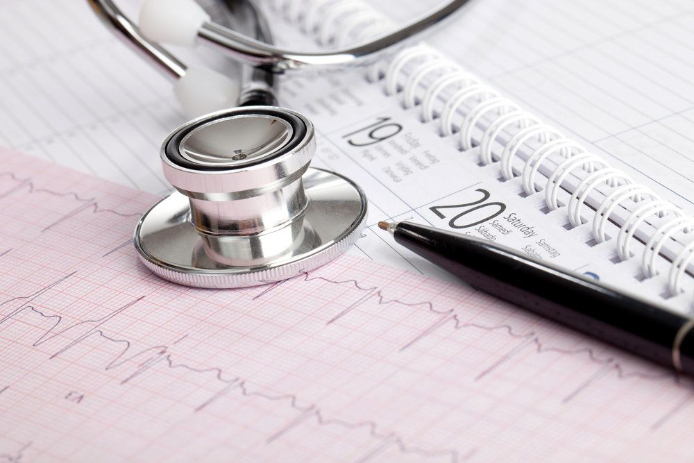 Stethoscope sitting on top of a calendar and diagnostic test results